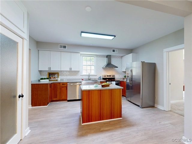 56 Mancha Ave, Claremont, VA 23899 - kitchen with stainless steel appliances, wall chimney range hood, a sink, and light wood-type flooring