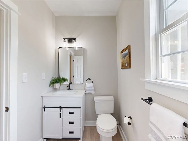 56 Mancha Ave, Claremont, VA 23899 - bathroom with toilet, vanity, wood finished floors, and baseboards