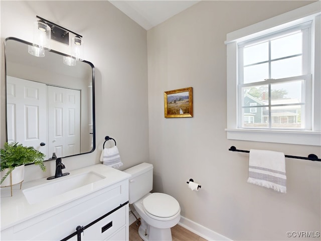 56 Mancha Ave, Claremont, VA 23899 - half bathroom featuring toilet, vanity, baseboards, and wood finished floors