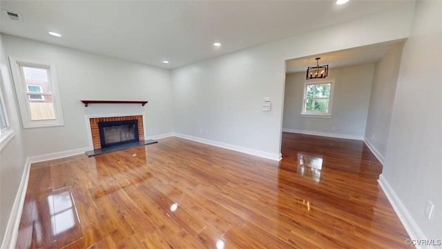 8803 Dena Dr, Henrico, VA 23229 - unfurnished living room featuring wood finished floors, a brick fireplace, a chandelier, baseboards, and recessed lighting