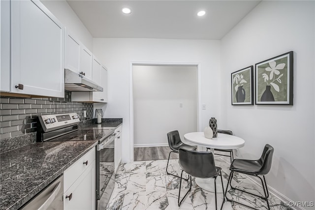 208 E 18th St, Richmond, VA 23224 - kitchen featuring stainless steel appliances, under cabinet range hood, light marble finish floors, white cabinetry, and dark stone counters