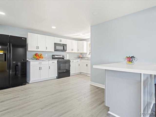 2519 Deerfield Dr, Petersburg, VA 23805 - kitchen with black appliances, light wood-style flooring, light countertops, white cabinets, and baseboards