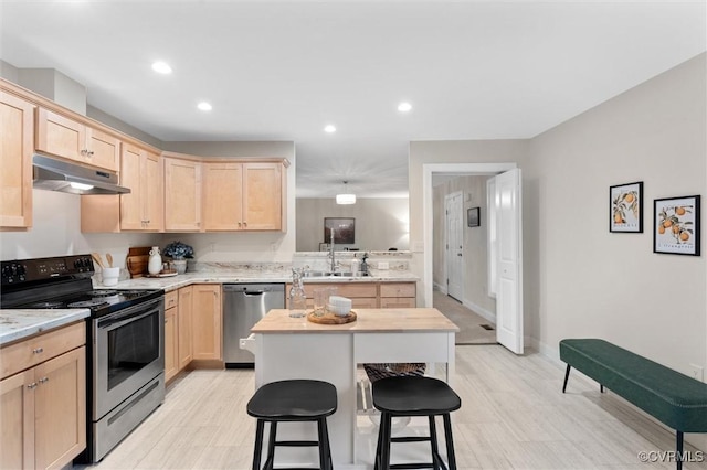 5239 Old Buckingham Rd, Powhatan, VA 23139 - kitchen with stainless steel appliances, light brown cabinetry, under cabinet range hood, a kitchen breakfast bar, and recessed lighting