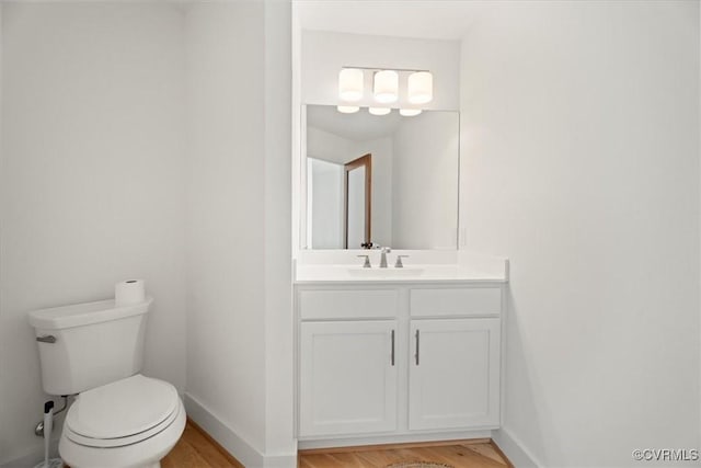 1665 Wilton Creek Rd, Hartfield, VA 23071 - half bath featuring vanity, toilet, wood finished floors, and baseboards