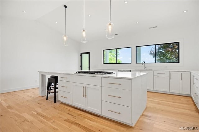 1665 Wilton Creek Rd, Hartfield, VA 23071 - kitchen with a sink, white cabinets, light wood finished floors, a kitchen island, and high vaulted ceiling