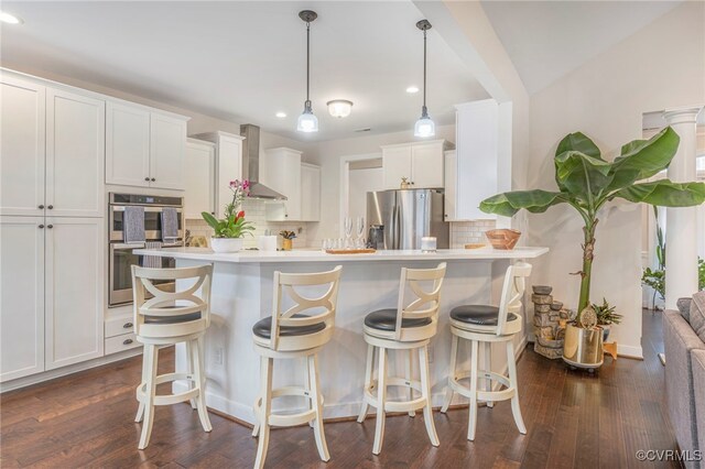 41 Pine Shadow Ct, Troy, VA 22974 - kitchen with stainless steel appliances, wall chimney exhaust hood, decorative backsplash, recessed lighting, and a kitchen bar