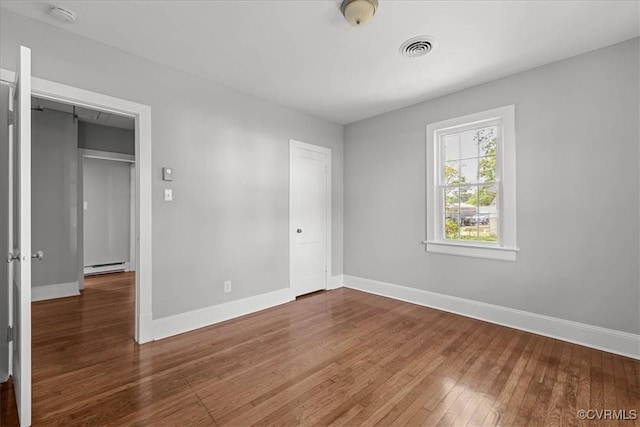 unfurnished bedroom with a baseboard radiator, baseboards, and hardwood / wood-style flooring