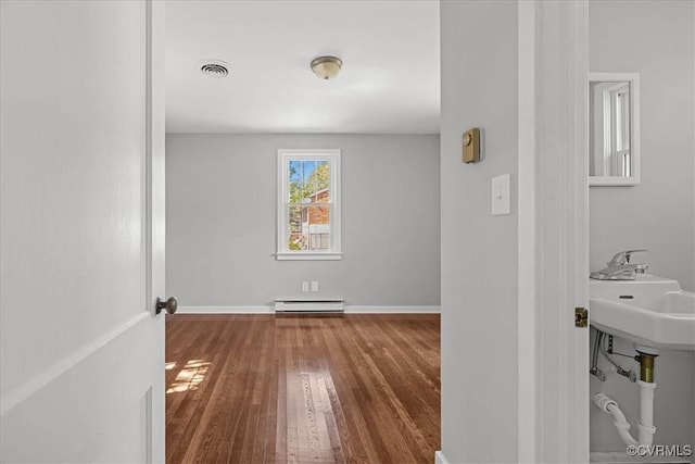 empty room with hardwood / wood-style flooring, baseboard heating, and baseboards