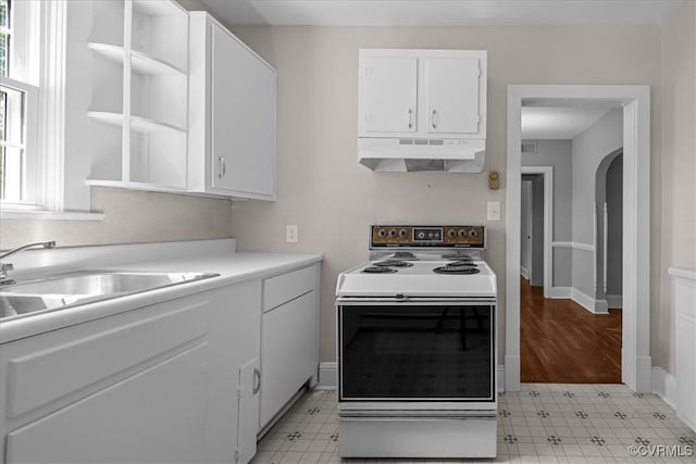 kitchen featuring under cabinet range hood, white range with electric cooktop, white cabinets, light flooring, and light countertops