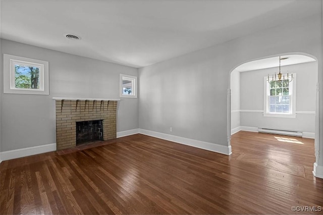 unfurnished living room featuring a baseboard radiator, wood finished floors, and plenty of natural light