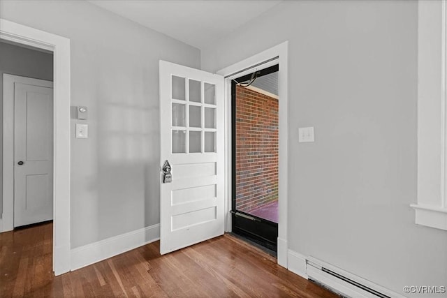 foyer entrance featuring a baseboard heating unit, wood finished floors, and baseboards