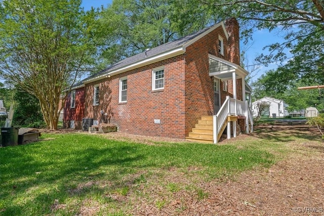 back of house featuring a chimney, a yard, and brick siding