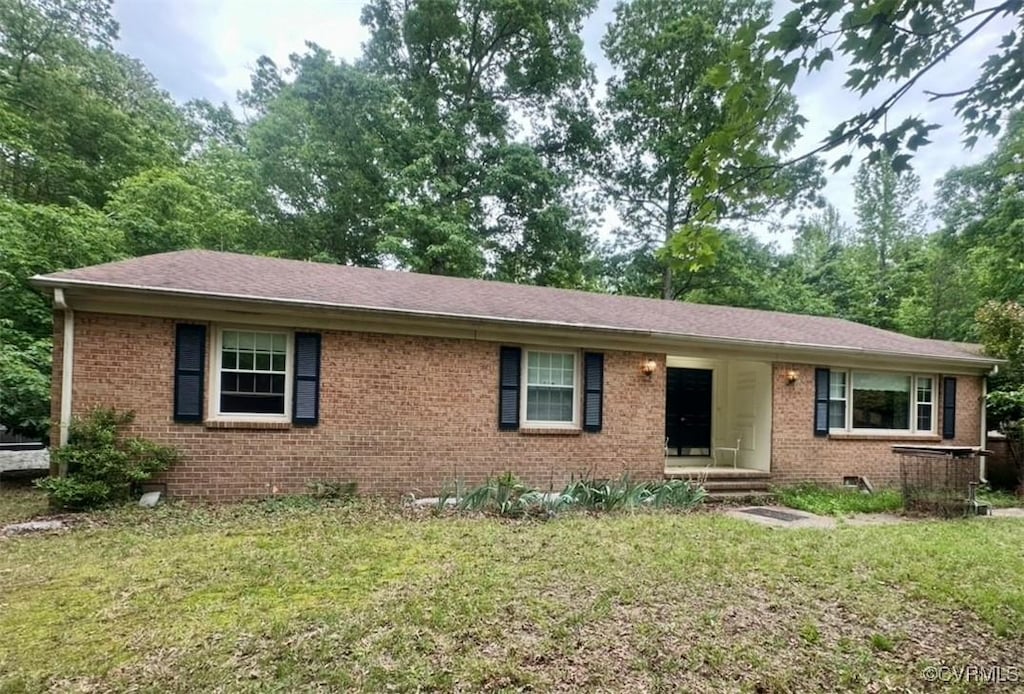 single story home featuring brick siding, a front lawn, and a shingled roof