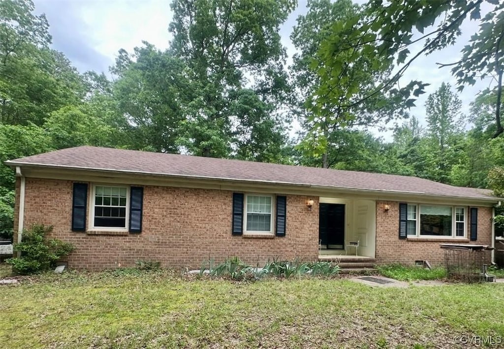 single story home featuring brick siding, a front lawn, and roof with shingles