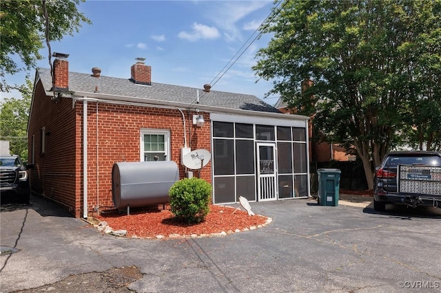 2405 Dumbarton Rd, Henrico, VA 23228 - back of property with oil tank, brick siding, a chimney, a sunroom, and roof with shingles
