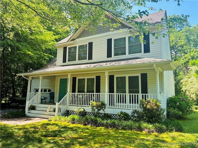 view of front of home with covered porch, a shingled roof, and a front lawn