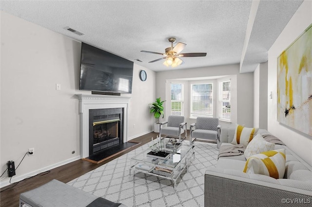15119 Winding Ash Dr, Chesterfield, VA 23832 - living room with wood finished floors, a fireplace with raised hearth, a ceiling fan, a textured ceiling, and baseboards