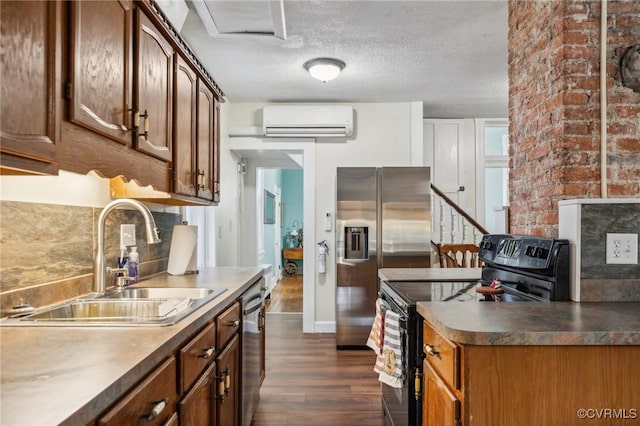 102 Market St, Onancock, VA 23417 - kitchen with a wall unit AC, stainless steel appliances, a sink, dark wood-style flooring, and brick wall