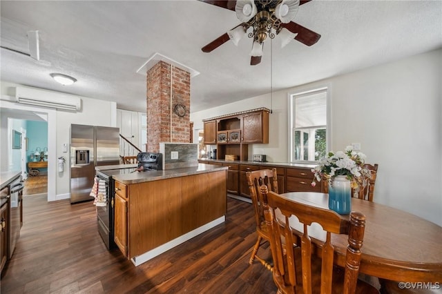 102 Market St, Onancock, VA 23417 - kitchen with stainless steel appliances, a wall mounted AC, a ceiling fan, dark wood finished floors, and a kitchen island