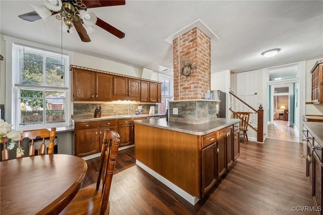 102 Market St, Onancock, VA 23417 - kitchen featuring dark wood-style flooring, ceiling fan, brown cabinetry, and backsplash
