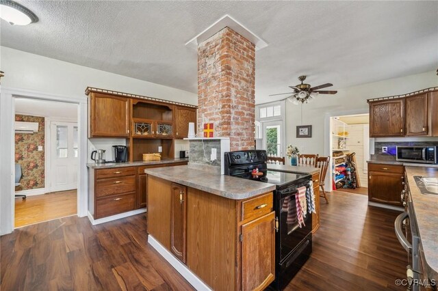 102 Market St, Onancock, VA 23417 - kitchen featuring black range with electric cooktop, stainless steel microwave, dark wood finished floors, ceiling fan, and a wall mounted AC