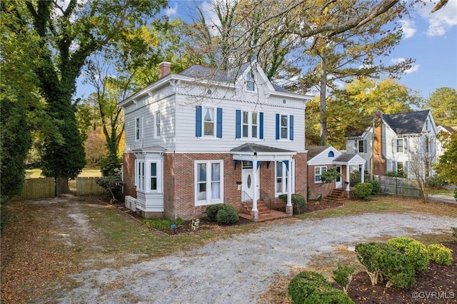 102 Market St, Onancock, VA 23417 - italianate-style house featuring brick siding, a chimney, fence, and dirt driveway