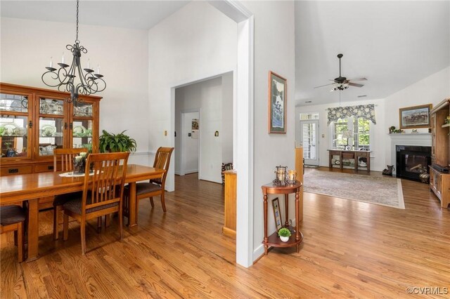 1629 Olmstead Dr, Powhatan, VA 23139 - dining room featuring high vaulted ceiling, a chandelier, light wood-style floors, ceiling fan, and a glass covered fireplace