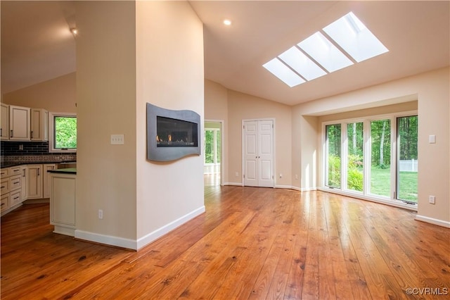 1396 Gray Fox Rd, Goochland, VA 23103 - unfurnished living room featuring vaulted ceiling, a skylight, light wood finished floors, and baseboards