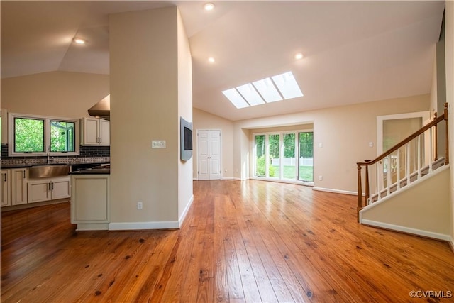 1396 Gray Fox Rd, Goochland, VA 23103 - unfurnished living room featuring a skylight, lofted ceiling, a sink, light wood-type flooring, and healthy amount of natural light