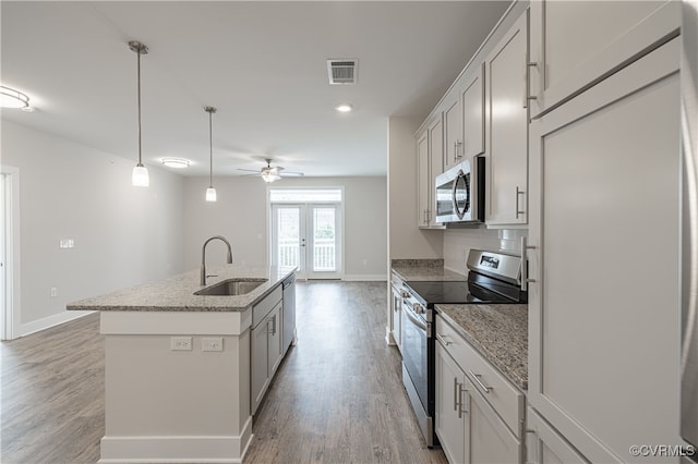 10530 Stony Bluff Dr Unit 305, Ashland, VA 23005 - kitchen featuring appliances with stainless steel finishes, a sink, light wood-type flooring, an island with sink, and baseboards