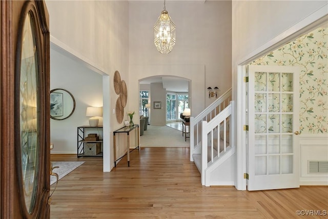 8831 Whistling Swan Rd, Chesterfield, VA 23838 - entryway featuring arched walkways, a high ceiling, a chandelier, stairs, and light wood-type flooring