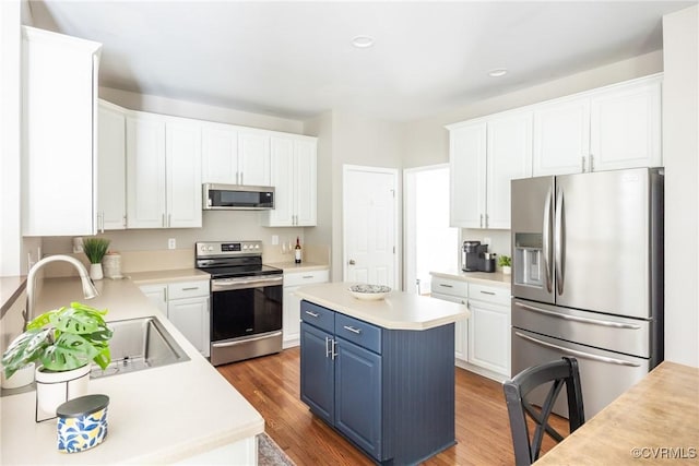12109 Jamieson Pl, Henrico, VA 23059 - kitchen featuring stainless steel appliances, blue cabinets, white cabinetry, light wood-style floors, and light countertops