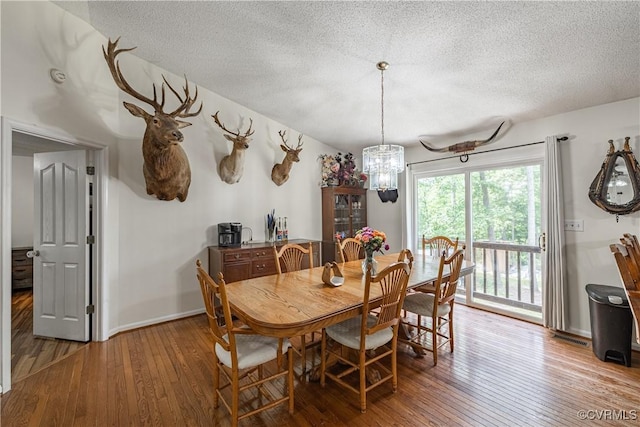 17063 Moores Mill Rd, Ruther Glen, VA 22546 - dining room with wood-type flooring, a textured ceiling, a chandelier, and baseboards