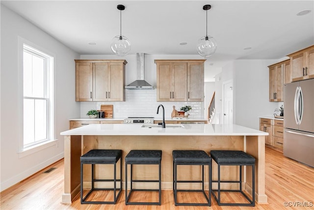2207 Fairmount Ave, Richmond, VA 23223 - kitchen with wall chimney range hood, freestanding refrigerator, a sink, and a kitchen bar