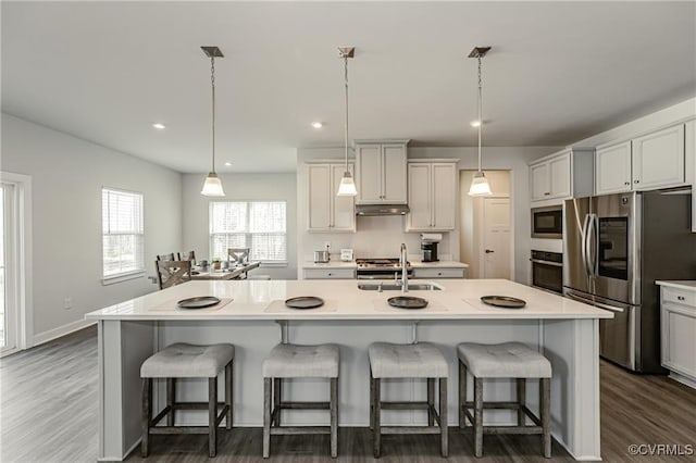 18160 Sagamore Dr, Chesterfield, VA 23120 - kitchen with appliances with stainless steel finishes, a breakfast bar, under cabinet range hood, light countertops, and recessed lighting