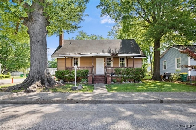 view of front of property with a porch, a chimney, and a front yard