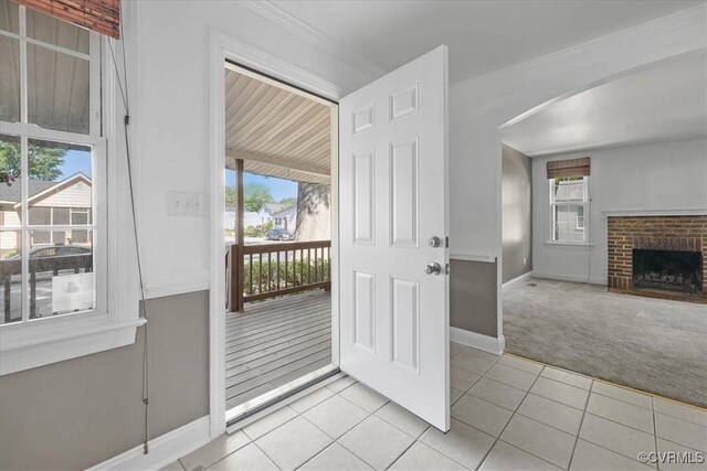 doorway to outside with arched walkways, light carpet, baseboards, light tile patterned floors, and a fireplace