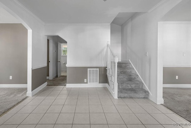 unfurnished living room with light colored carpet, stairs, arched walkways, light tile patterned floors, and crown molding
