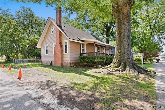 view of property exterior with a chimney and covered porch