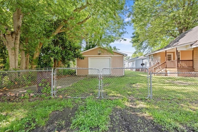 view of yard featuring an outdoor structure, a detached garage, driveway, and a gate