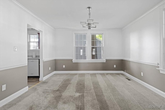 carpeted spare room featuring ornamental molding, a chandelier, and baseboards