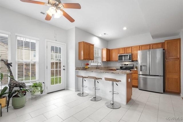 2603 Mountainberry Ct, Glen Allen, VA 23060 - kitchen with appliances with stainless steel finishes, a peninsula, a sink, brown cabinets, and a ceiling fan
