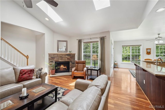 14109 Rigney Dr, Midlothian, VA 23113 - living room featuring a skylight, ceiling fan, a stone fireplace, lofted ceiling, and light wood-style flooring