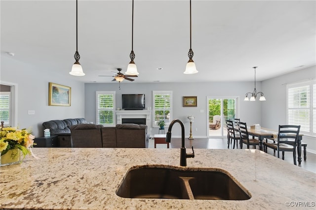 13524 Thomaswoods Ln, Ashland, VA 23005 - kitchen featuring a sink, ceiling fan, a fireplace, decorative light fixtures, and light stone counters