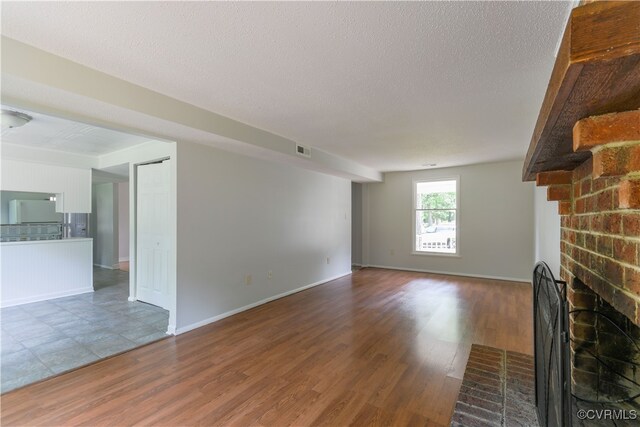 10002 Laurel Lakes Dr, Glen Allen, VA 23060 - unfurnished living room featuring a fireplace, wood finished floors, a textured ceiling, and baseboards