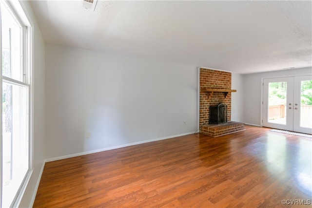 10002 Laurel Lakes Dr, Glen Allen, VA 23060 - unfurnished living room featuring french doors, wood finished floors, a fireplace, a textured ceiling, and baseboards