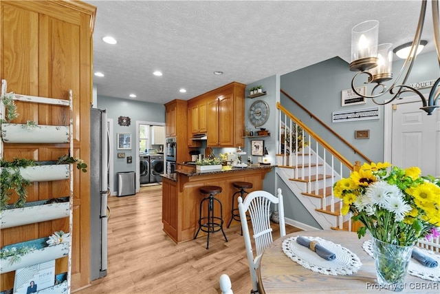 6304 Belroi Rd, Abingdon, VA 23061 - kitchen with separate washer and dryer, light wood-style flooring, a peninsula, appliances with stainless steel finishes, and brown cabinetry
