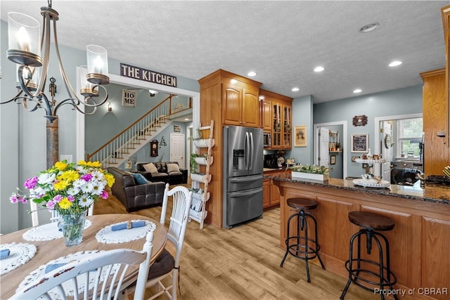 6304 Belroi Rd, Abingdon, VA 23061 - kitchen with stainless steel refrigerator with ice dispenser, brown cabinets, glass insert cabinets, light wood-style floors, and dark stone counters