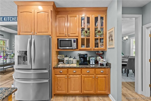 6304 Belroi Rd, Abingdon, VA 23061 - kitchen featuring appliances with stainless steel finishes, light wood-type flooring, dark stone counters, glass insert cabinets, and a chandelier