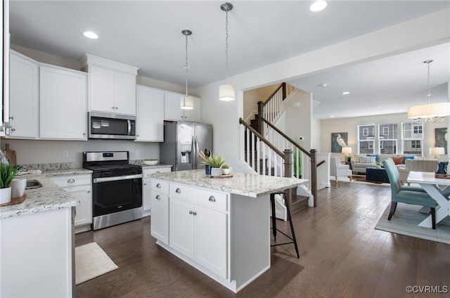 5200 Gower Pl, Glen Allen, VA 23059 - kitchen with stainless steel appliances, a kitchen breakfast bar, hanging light fixtures, white cabinetry, and dark wood-type flooring